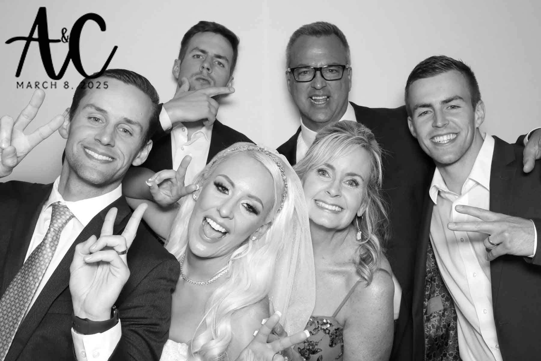 Bride and guests smiling and making peace signs in the photo booth