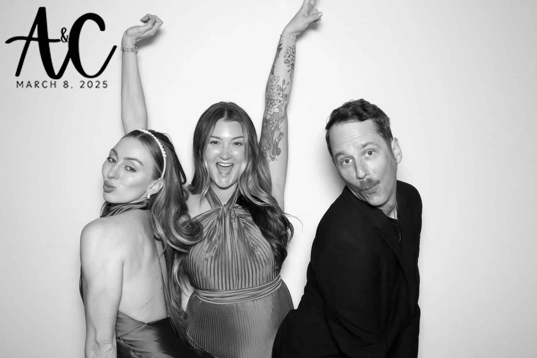 Three guests making silly poses at a wedding against a white backdrop